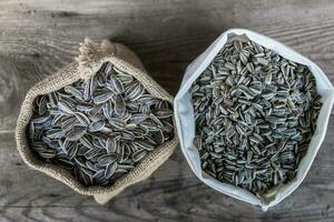 bag with variety of sunflower seeds on rustic wooden background photo