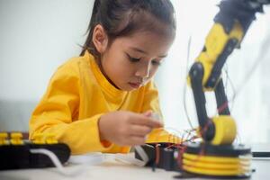 vástago educación concepto. asiático estudiantes aprender a hogar por codificación robot brazos en provenir, matemáticas Ingenieria Ciencias tecnología computadora código en robótica para niños' conceptos. foto