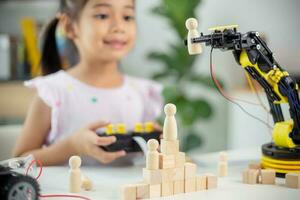 STEM education concept. Asian students learn at home by coding robot arms in STEM, mathematics engineering science technology computer code in robotics for kids' concepts photo