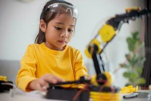 STEM education concept. Asian students learn at home by coding robot arms in STEM, mathematics engineering science technology computer code in robotics for kids' concepts. photo