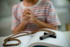 Christian concept. Little Asian girl praying withholding the cross. Concepts of hope, faith, Christianity, religion, photo