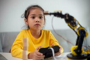STEM education concept. Asian students learn at home by coding robot arms in STEM, mathematics engineering science technology computer code in robotics for kids' concepts. photo