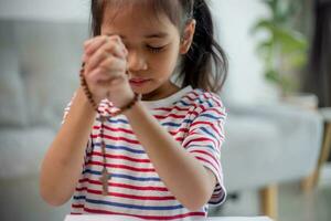 cristiano concepto. pequeño asiático niña Orando reteniendo el cruzar. conceptos de esperanza, fe, cristiandad, religión, foto