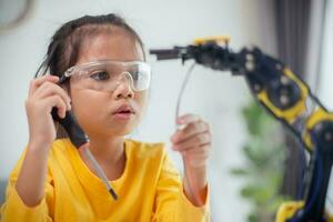 STEM education concept. Asian students learn at home by coding robot arms in STEM, mathematics engineering science technology computer code in robotics for kids' concepts. photo