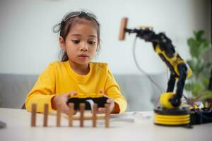 STEM education concept. Asian students learn at home by coding robot arms in STEM, mathematics engineering science technology computer code in robotics for kids' concepts. photo