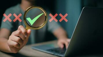 Focusing on the right choice concept. Hand holds magnifying glass focusing on the checkmark or tick right symbol next to wrong cross icons. photo