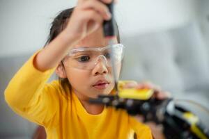 vástago educación concepto. asiático estudiantes aprender a hogar por codificación robot brazos en provenir, matemáticas Ingenieria Ciencias tecnología computadora código en robótica para niños' conceptos. foto