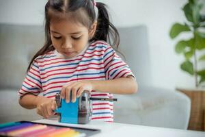 Student child girl using Pencil sharpener while doing homework. education concept. photo