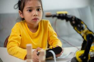 STEM education concept. Asian students learn at home by coding robot arms in STEM, mathematics engineering science technology computer code in robotics for kids' concepts. photo