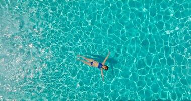 Top down view of a woman in blue swimsuit lying on her back in the pool. video