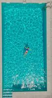 Top down view of a woman in blue swimsuit lying on her back in the pool. video