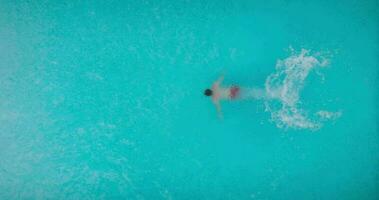 aéreo ver de un hombre en rojo pantalones cortos nadando en el piscina video