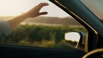 visie van auto venster Aan weg en hand- Mens wie schijven de voertuig en gebaren naar ritme van muziek. zonnig lucht, ontspannend, genieten van weg reis en gevoel de lucht en vrijheid video