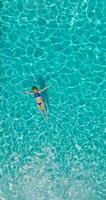 Top down view of a woman in blue swimsuit lying on her back in the pool. video