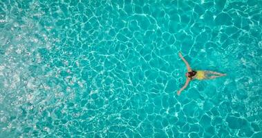 aereo Visualizza di un' donna nel giallo costume da bagno nuoto nel il piscina. estate stile di vita video