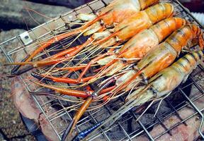 Home cooks are grilling prawns on a charcoal stove. photo