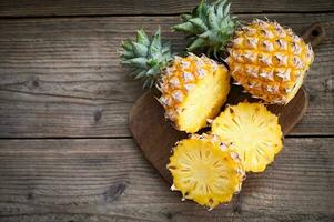 fresh pineapple tropical fruits summer, pineapple slice on plate for food fruit ripe pineapple on wooden background - top view photo