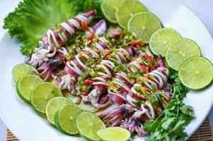 Thai food seafood plate with herb and spices, Steamed squid with lemon spicy chili and lemon sauce squid steamed with lime - top view photo