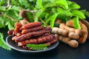 Tamarindo pelar en plato tropical frutas verano, Tamarindo dulce para comida Fruta maduro tamarindos en plato y blanco antecedentes - parte superior ver foto