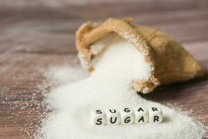 white sugar for food and sweets dessert candy heap of sweet sugar crystalline granulated, Sugar on sack and wooden background photo