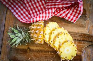 fresh pineapple tropical fruits summer, pineapple slice on plate for food fruit ripe pineapple on wooden background - top view photo