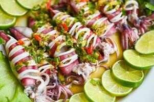 Steamed squid with lemon spicy chili and lemon sauce squid steamed with lime, Thai food seafood plate with herb and spices - top view photo
