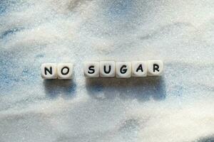 no sugar text blocks with white sugar on wooden background, suggesting dieting and eat less sugar for health concept photo