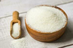 blanco azúcar para comida y dulces postre caramelo montón de dulce azúcar cristalino granulado, azúcar en de madera antecedentes foto