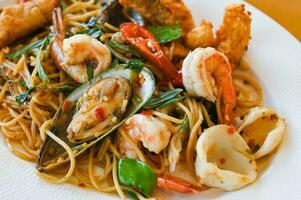 noodles plate with spaghetti pasta stir fried with vegetables herb spicy tasty appetizing asian noodles mix seafood stir fried shrimp squid shellfish fish with basil and chilli pepper photo