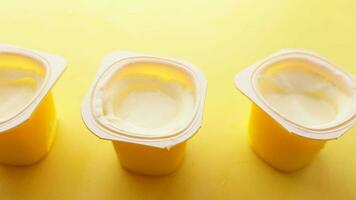 Fresh yogurt in a plastic container on yellow background video