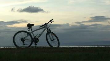 silueta de un bicicleta en contra el antecedentes de el puesta de sol en el lago foto