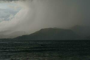 tormenta terminado el mar con montañas en el antecedentes foto