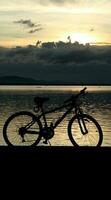 silhouette of a bicycle against the background of the sunset on the lake photo