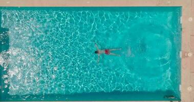 Aerial view of a man in red shorts swimming in the pool video