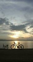 silhouette of a bicycle against the background of the sunset on the lake photo
