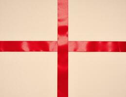 Red silk ribbon on a beige background, top view photo