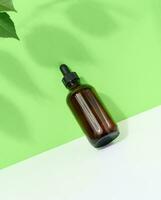 Brown glass bottle with a pipette on a green-white background, a container for aromatic oils and cosmetics photo