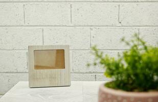 Concept shot of blank wooden photo frame on gray wooden table and brick wall background