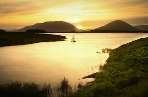 Beautiful golden hour sunset scenery of lake and mountains at Connemara National park in County Galway, Ireland photo