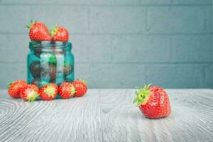 Product shot of delicious red strawberries on wooden table with brick wall background photo
