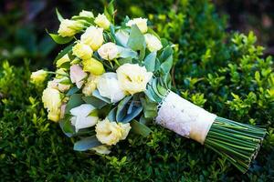 beautiful bridal bouquet lying on green grass photo