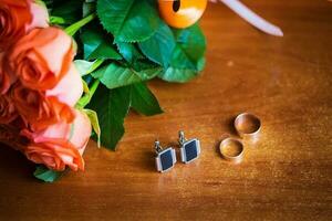 bridal bouquet, groom's ring and cuff links are on table photo