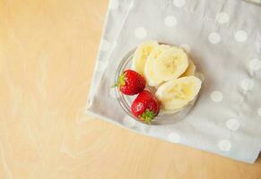 strawberry and banana on a glass plate on a wooden background. photo