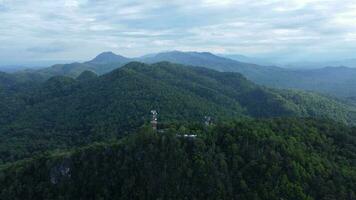 Communication tower, radio tower, telecommunication tower or transmission tower in the forest on the mountain with clouds and blue sky background. video