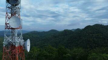 Communication tower, radio tower, telecommunication tower or transmission tower in the forest on the mountain with clouds and blue sky background. video