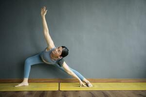 asian woman doing yoga pose in home living room photo