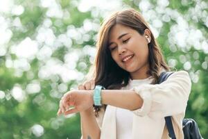 Young asian woman using smartwatch and listening to music in the park photo