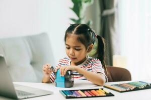 asiático pequeño niño niña dibujo con color lapices en vivo habitación a hogar foto