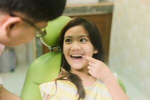 linda asain niña durante dental tratamiento a moderno clínica foto