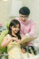 A smiling girl with thumb raised having teeth examination at dental clinic. People, medicine, stomatology and health care concept photo